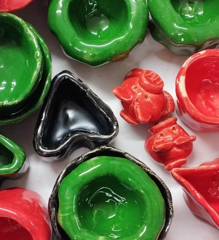 Grüne, rote und eine schwarze Keramikschale in verschiedenen Formen, darunter Herzform und rund, auf weißem Untergrund