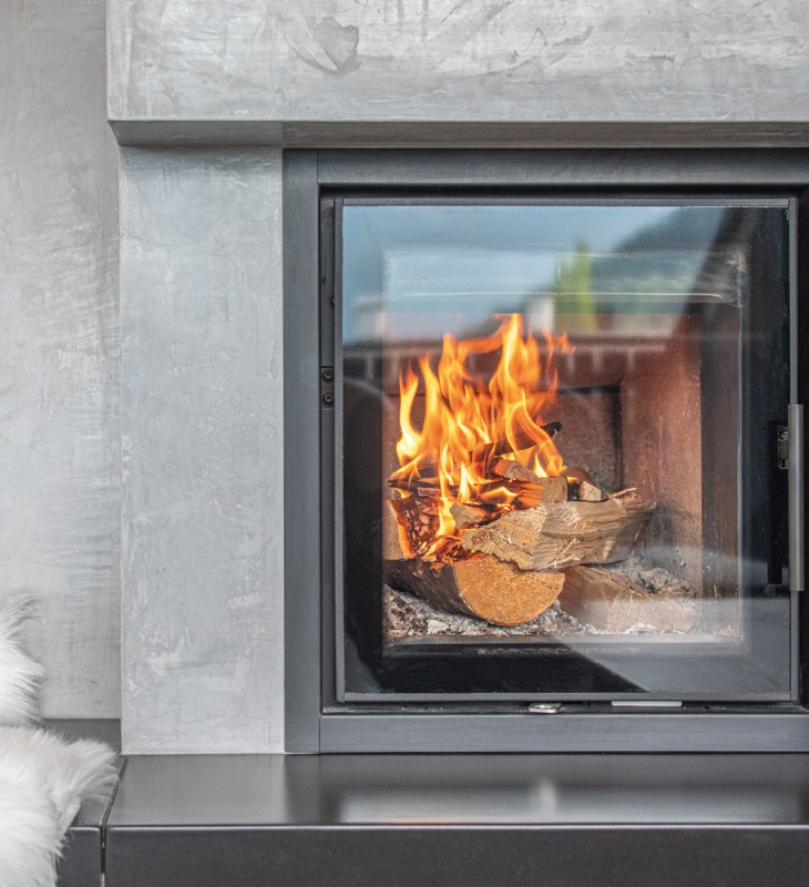 Moderner Kamin mit brennendem Holz in einem grauen Betonrahmen