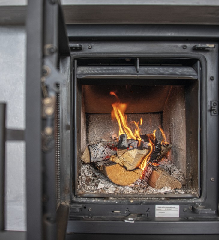 Holzofen mit brennendem Feuer und Holzscheiten im Inneren