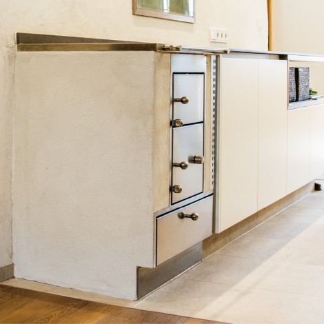 Küchenzeile mit eingebautem Ofen und Schubladen in hellem Raum mit Holz- und Fliesenboden
