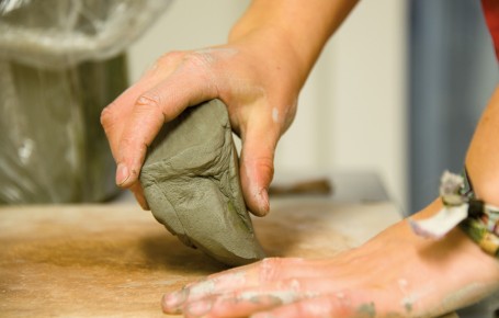 Hände formen einen Klumpen Ton auf einer Arbeitsfläche