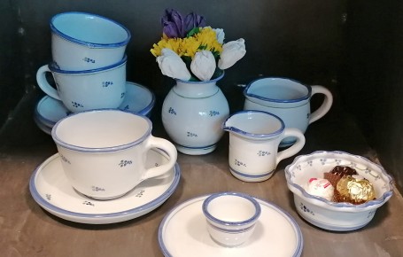 Porzellan-Kaffeegeschirr mit blauem Rand und kleinem Blumendekor, bestehend aus Tassen, Untertassen, Milchkännchen, Zuckerdose, Eierbecher und Vase mit künstlichen Blumen