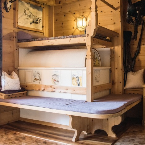 Holzraum mit Bauernofen, Sitzbank mit Polster und Kissen, Holzschrank und Wandlampe