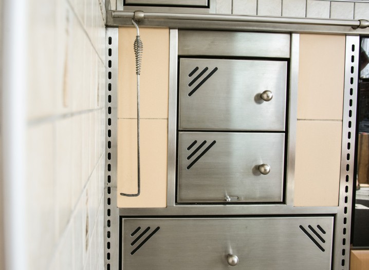 Edelstahlholzofen mit mehreren Fächern und runden Griffen an einer beige gekachelten Wand
