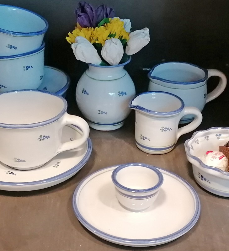 Porzellan-Kaffeegeschirr mit blauem Rand und kleinem Blumendekor, bestehend aus Tassen, Untertassen, Milchkännchen, Zuckerdose, Eierbecher und Vase mit künstlichen Blumen