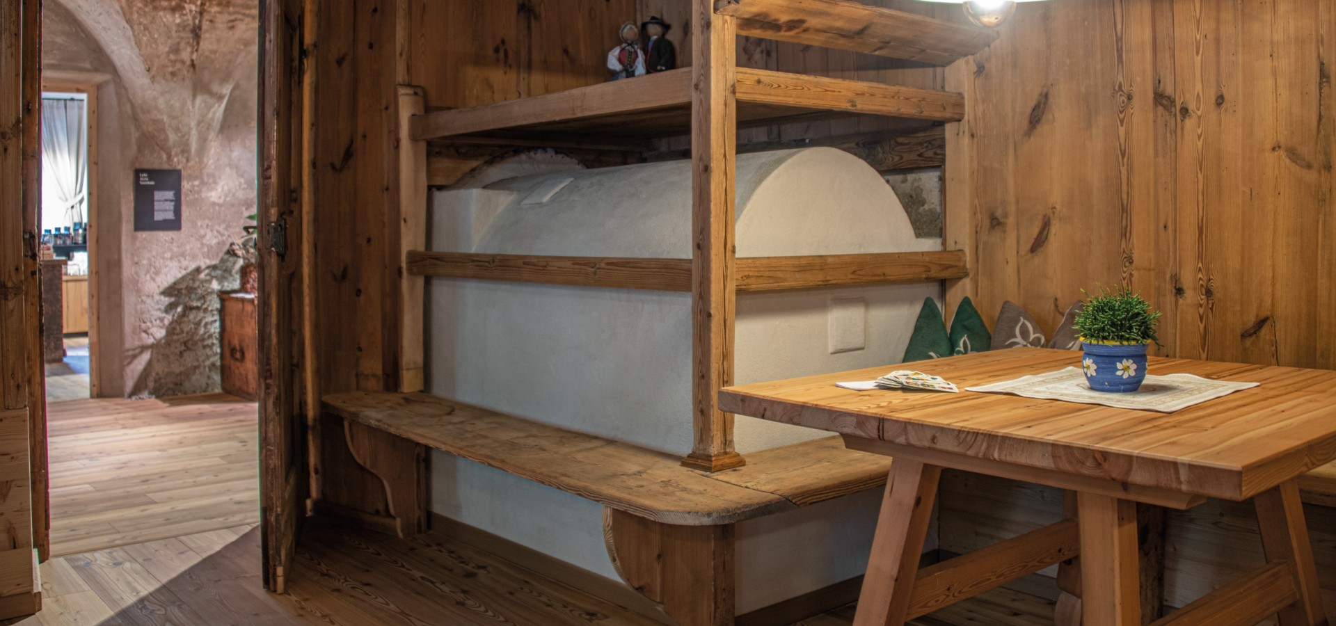 Holzbank mit gepolstertem Sitzkissen in einem rustikalen Raum mit Holztisch und Topfpflanze