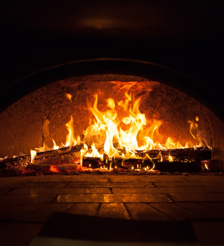 Flammen und brennende Holzscheite in einem gemauerten Ofen mit gewölbter Decke