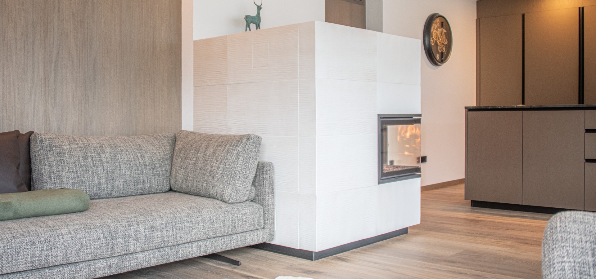 Wohnzimmer mit grauem Sofa, weißem Kamin und Holzboden mit Tierfellteppich