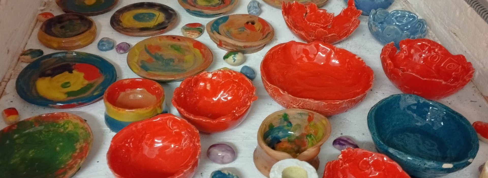 Verschiedene bunte, handgefertigte Keramikschalen und Teller